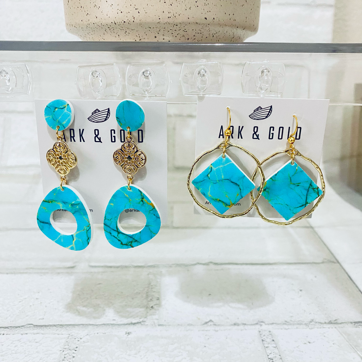 Turquoise earrings with gold accents on Ark & Gold branded cards against a white background.