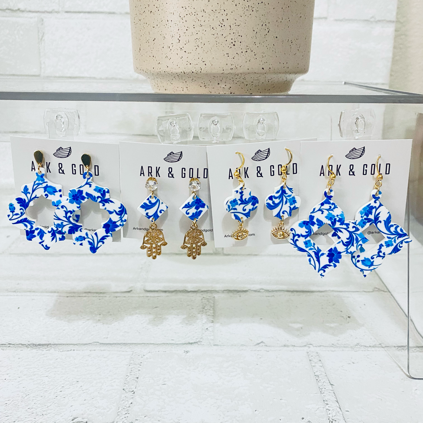Blue and gold earrings on 'ARK & GOLD' branded cards against a white background
