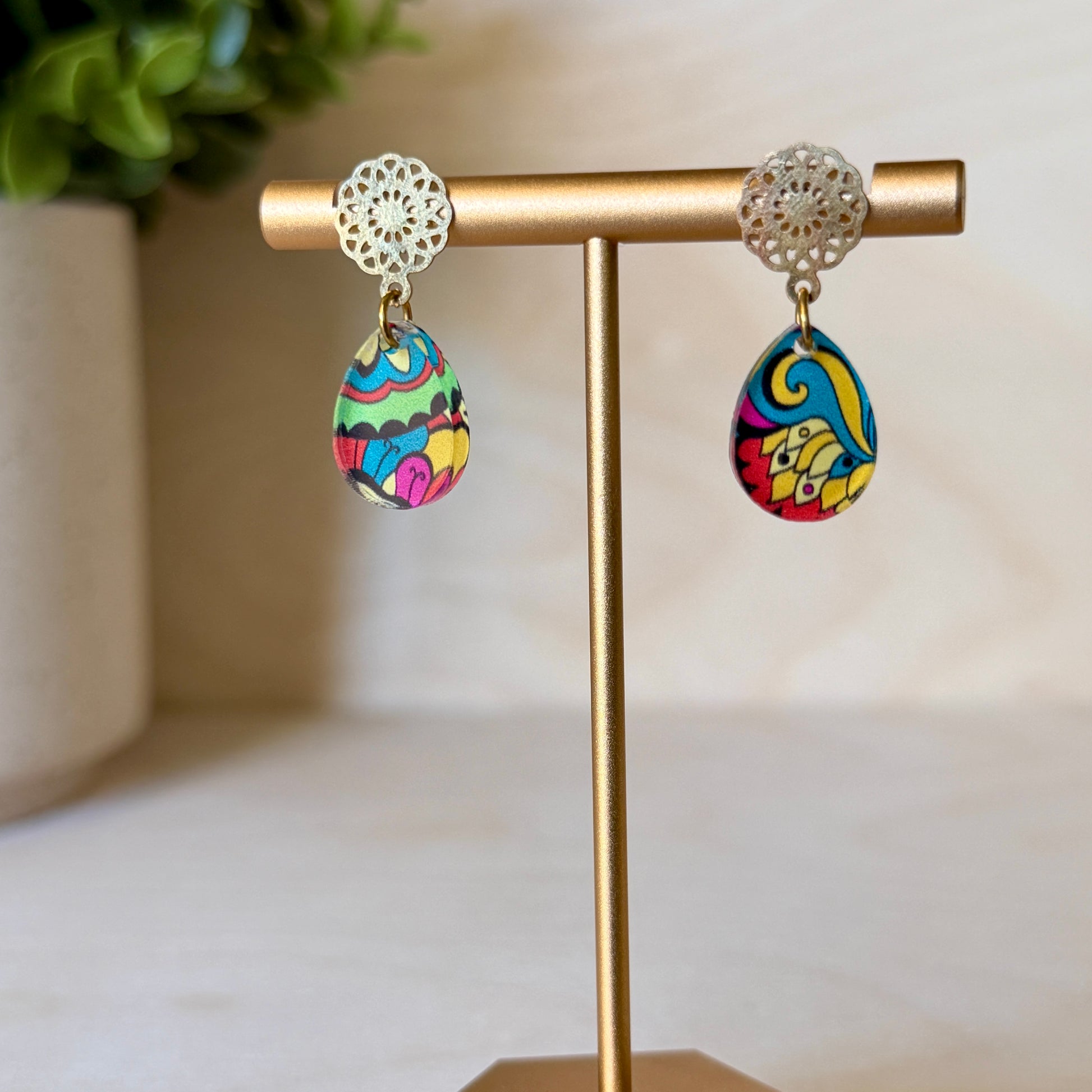 Colorful earrings on a gold earring stand with a blurred background