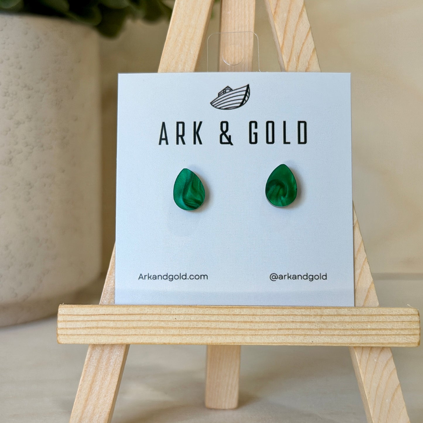 Green earrings on a 'ARK & GOLD' branded card with a wooden stand.