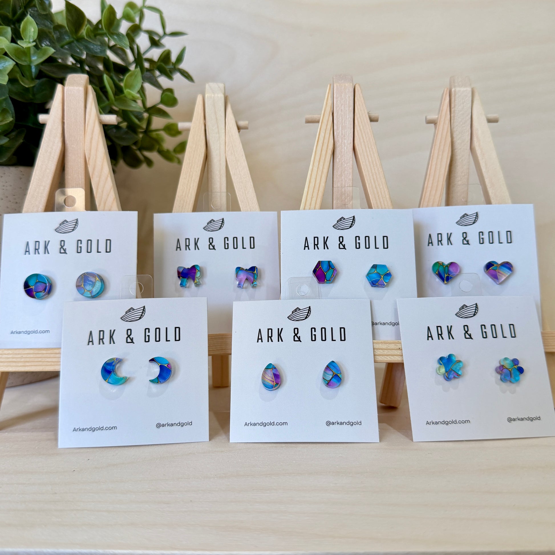 ARK & GOLD earrings on display with branded cards against a neutral background